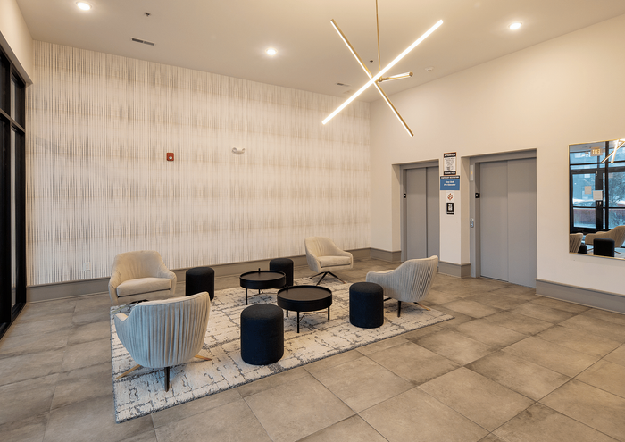 Elegant lobby with modern seating, chic lighting fixture, and sleek elevators.