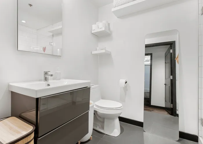 Sleek and modern bathroom with a stylish sink, wall mirror, and open shelving.