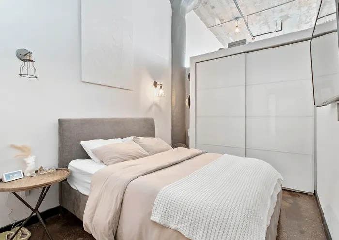 A stylish bedroom with a comfortable bed, modern lighting, and sleek storage space.