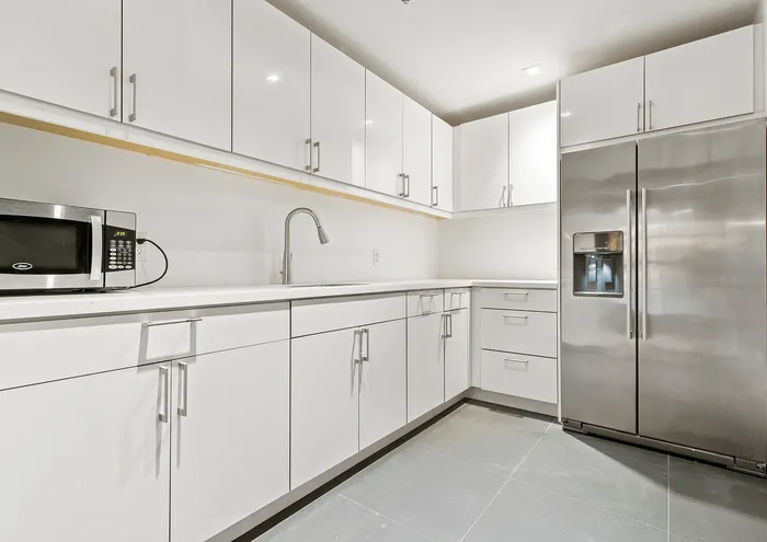 Bright and modern kitchen with white cabinetry and stainless steel appliances.