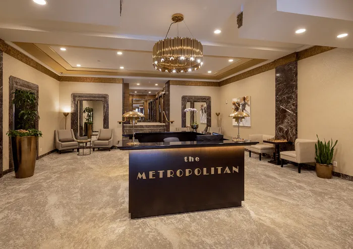 Elegant lobby of The Metropolitan with chic seating, modern decor, and a grand chandelier.