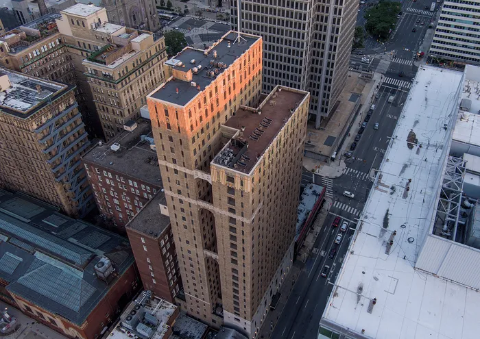 Aerial view of a sunlit high-rise building in a vibrant urban setting, showcasing modern architecture and cityscape.