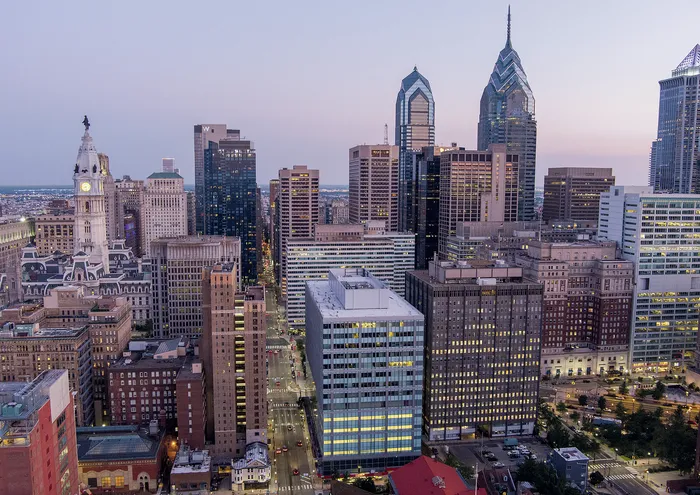 Breathtaking aerial view of an illuminated urban skyline at dusk, featuring modern skyscrapers and historic architecture.