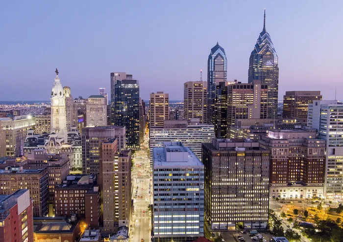 Stunning aerial view of a bustling cityscape at dusk with illuminated skyscrapers and historic buildings.