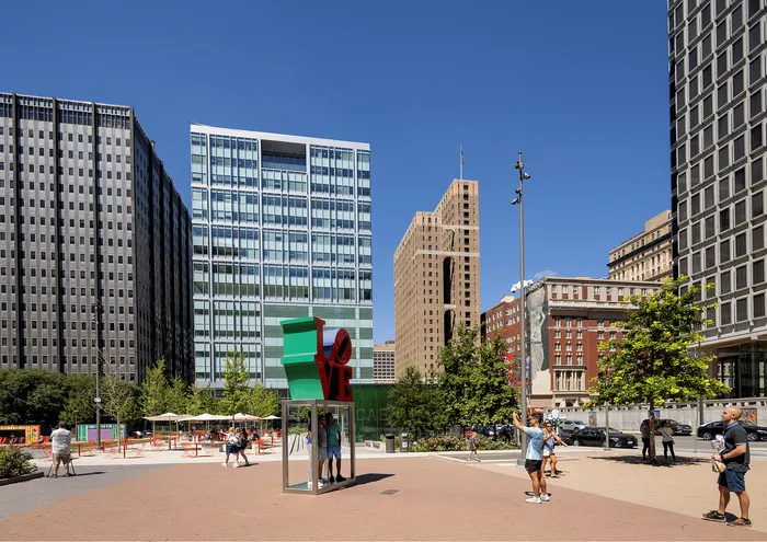Vibrant city scene with modern skyscrapers and iconic LOVE sculpture under a clear blue sky.