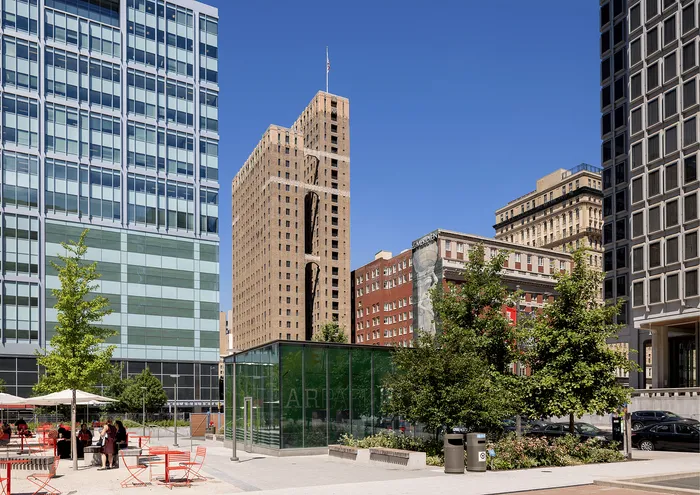 Vibrant city plaza surrounded by modern skyscrapers and lush greenery.