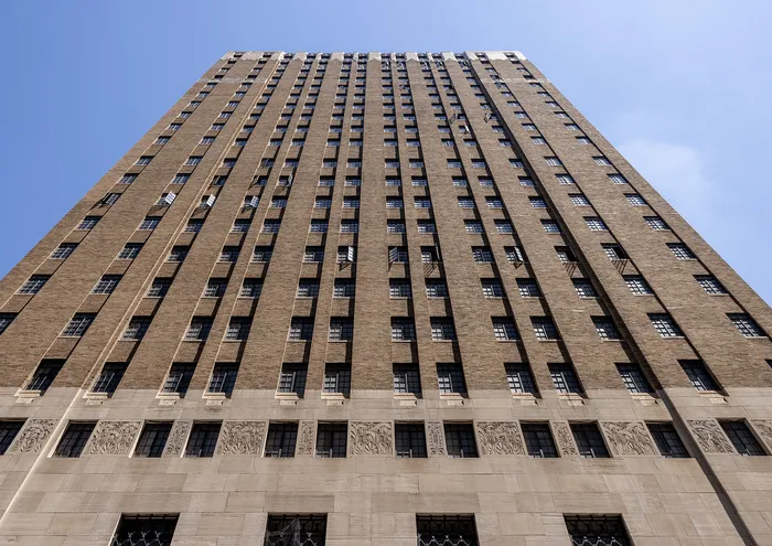 Majestic high-rise building with intricate facade against a clear blue sky.