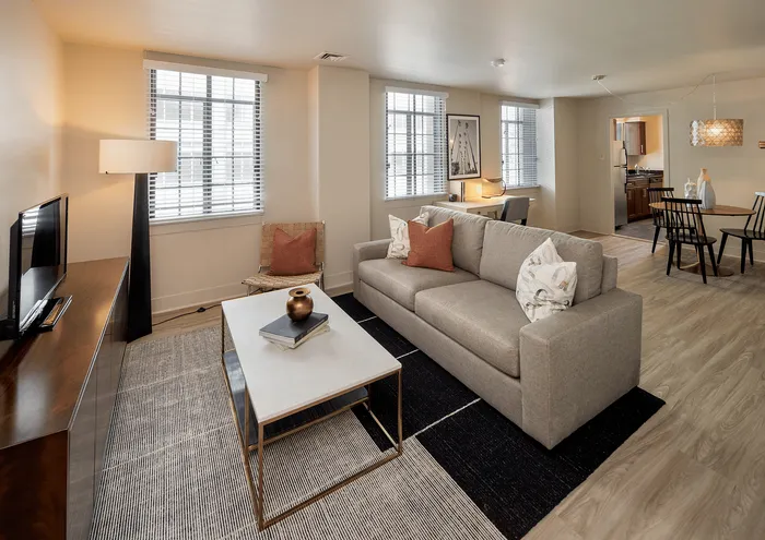 Stylish living room with a modern gray sofa, chic decor, and open dining area.