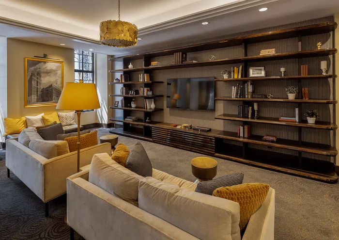 Warm and stylish living room with plush sofas, built-in shelving, and a modern chandelier.