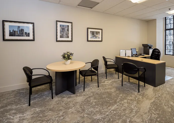 Chic office space with framed cityscape art, a round table with chairs, and a sleek desk setup.