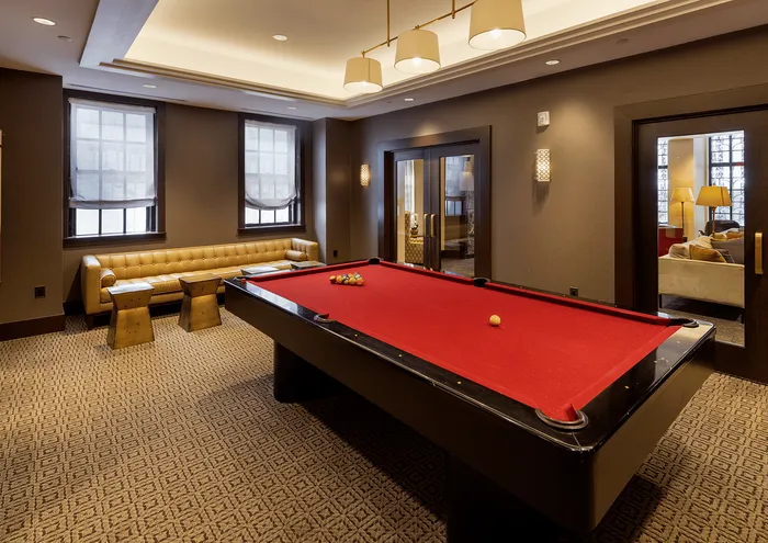 Chic entertainment room featuring a red felt pool table, stylish seating, and elegant lighting.