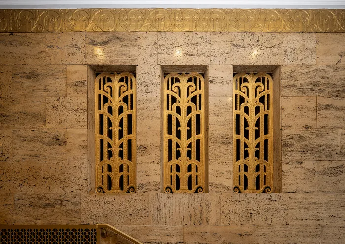 Luxurious Art Deco wall with intricate gold detailing and warm stone finish.