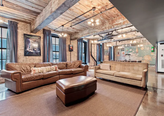 Stylish loft with exposed brick walls, wooden ceiling beams, and cozy leather couches.