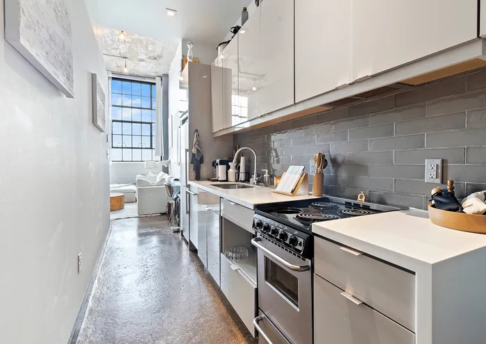 Sleek, narrow kitchen with modern appliances and a large window view.