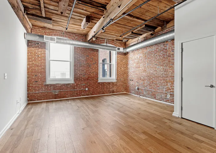 Bright loft with exposed brick walls, hardwood floors, and industrial ceiling in a modern open space.