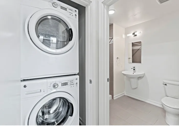 Bright modern bathroom with a sleek laundry area featuring a stacked washer and dryer.