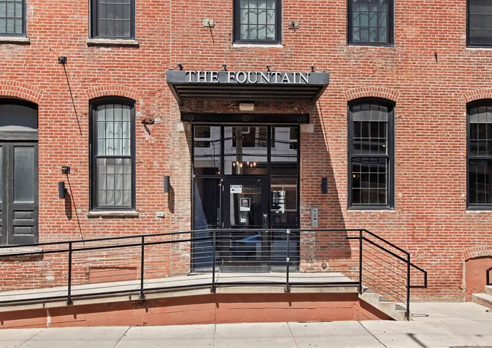 Charming brick exterior of The Fountain Apartments with large windows and a modern entrance.