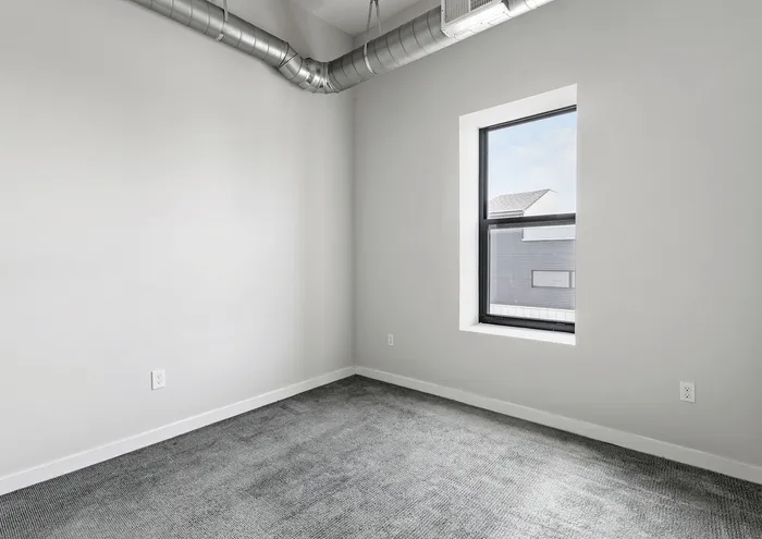 Bright room with modern exposed ductwork and a large window for natural light.