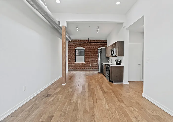 Chic urban apartment with exposed brick wall, sleek kitchen, and hardwood flooring.