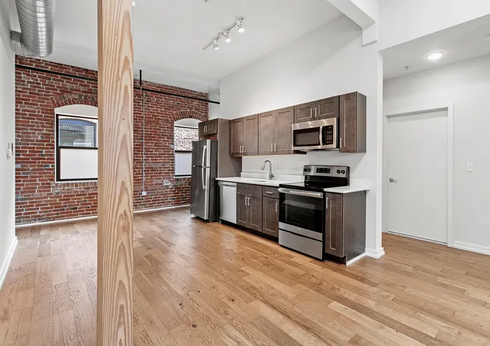 Modern kitchen with exposed brick walls, stainless steel appliances, and wooden cabinetry.