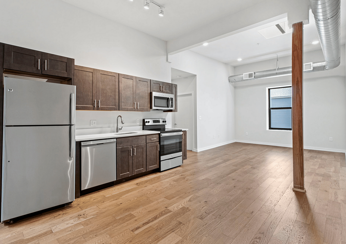 Stylish apartment kitchen with modern stainless steel appliances and open-concept living space.