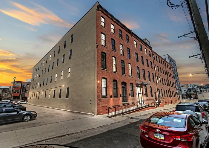 Charming brick apartment building with modern amenities in an urban setting at sunset.