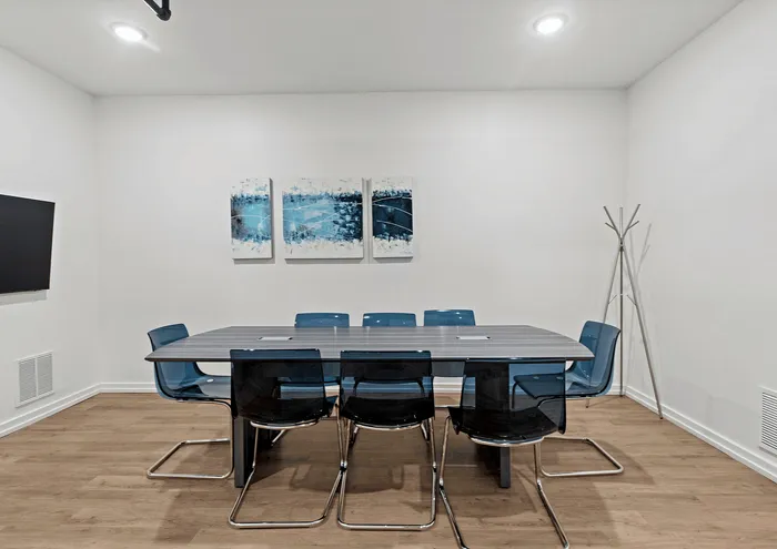 Chic conference room with modern table and vibrant blue chairs, accented by abstract artwork.