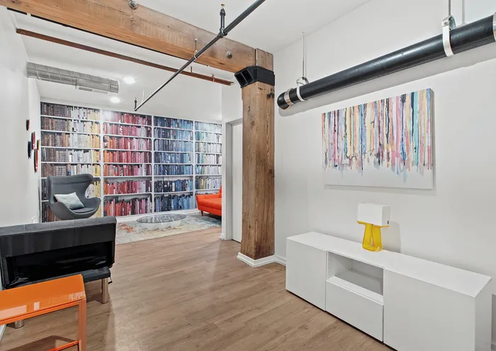 Contemporary loft with colorful bookshelf mural, wooden beams, and modern furnishings.