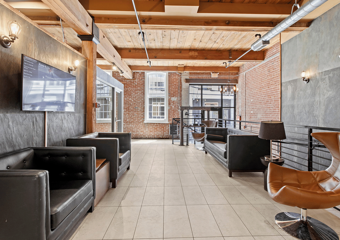 Stylish urban lounge with leather seating, exposed brick walls, and modern lighting.