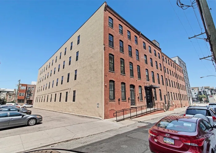 Brick and beige modern apartment building with large windows and street parking.