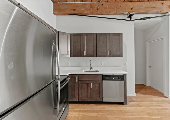 Modern kitchen with stainless steel appliances, wooden cabinets, and exposed wooden beams.