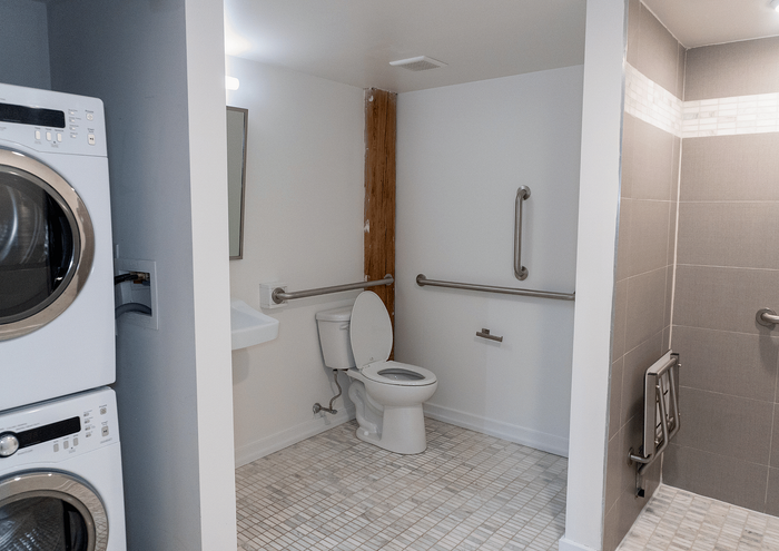Modern bathroom equipped with accessibility features and in-unit laundry appliances.