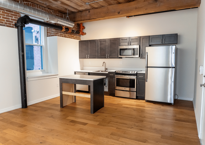 Sleek loft kitchen with modern stainless steel appliances and exposed brick detailing.