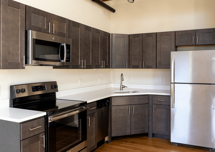 Contemporary kitchen design with dark wood cabinets, stainless steel appliances, and white countertops.