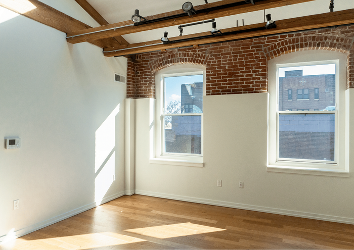 Bright and airy loft with exposed brick walls, wooden beams, and large windows.