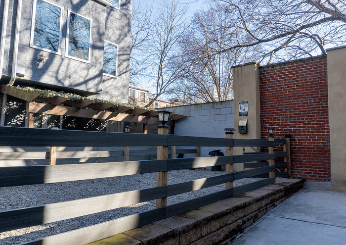Cozy and private outdoor courtyard with modern wooden fencing and brick wall backdrop.
