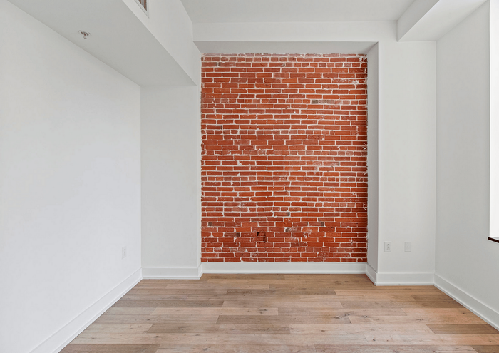 Modern apartment interior featuring an exposed red brick wall and elegant wood flooring.