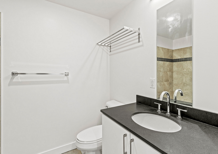 Contemporary bathroom featuring a stylish black countertop, chrome fixtures, and elegant tiled wall.