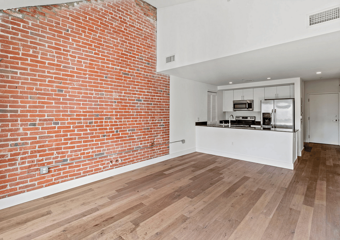 Contemporary apartment with exposed brick wall and modern kitchen.