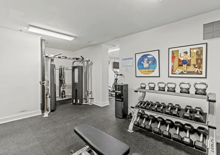 Modern apartment fitness center with weight racks, multifunctional gym equipment, and motivational art.