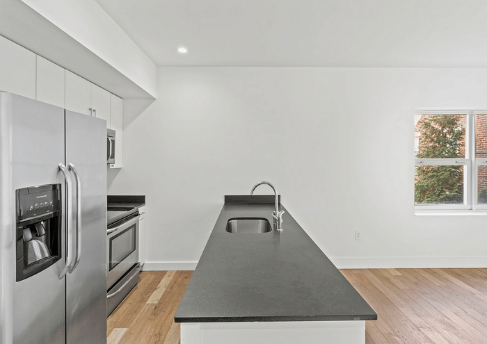 Contemporary kitchen featuring stainless steel appliances, black countertops, and natural light.