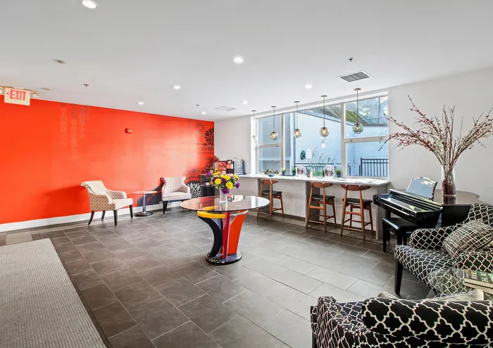 Contemporary lounge area featuring bold red accent wall, stylish seating, and a chic bar with pendant lighting.