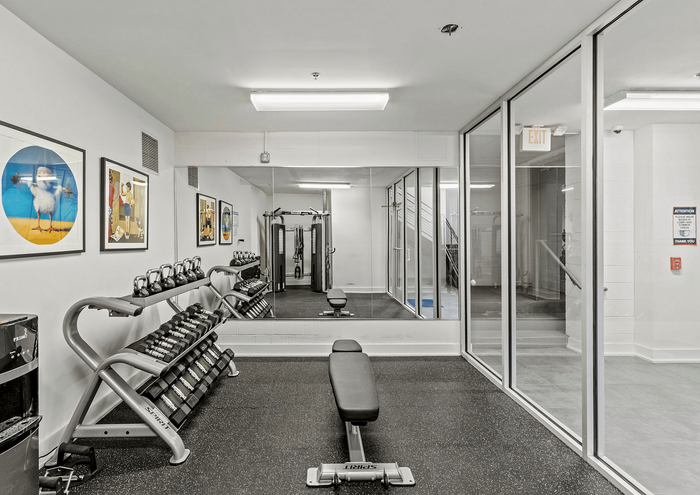 Well-equipped gym room with free weights, modern exercise machines, and wall art decor.