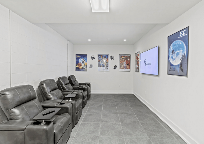 Modern home theater featuring leather recliners, classic movie posters, and a large flat-screen TV.