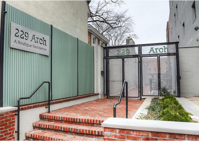 Elegant entrance of 229 Arch showcasing a modern boutique residence with brick steps and green paneling.