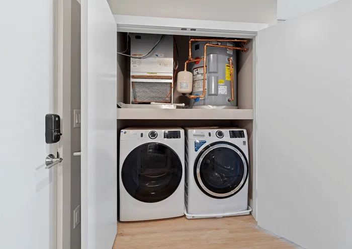 Sleek closet laundry area with modern washer, dryer, and water heater setup.