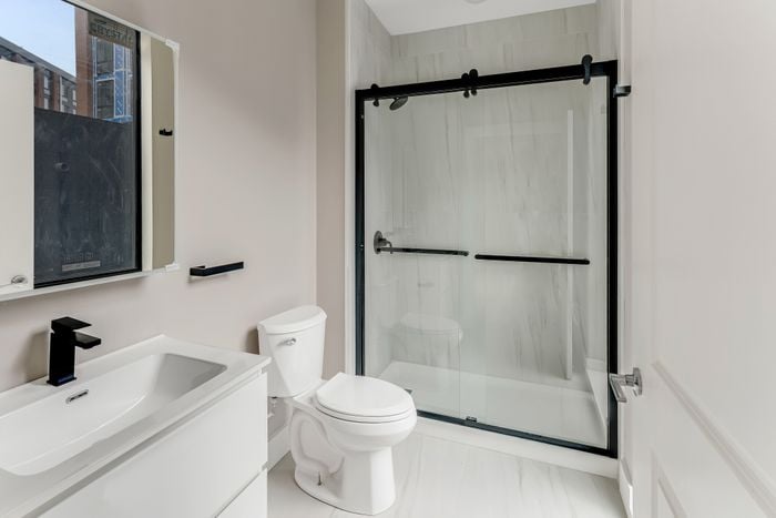 Modern bathroom with sleek design featuring a glass-enclosed shower, elegant white sink, and contemporary fixtures.