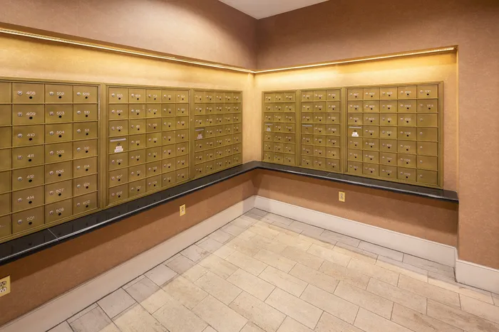 Elegant mailroom corner with neatly arranged golden mailboxes and warm ambient lighting.
