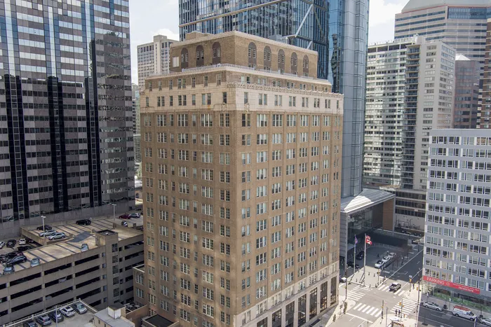 Elegant urban high-rise building nestled among skyscrapers in a bustling cityscape, offering vibrant city living.