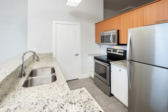 Modern kitchen with sleek stainless steel appliances, elegant granite countertops, and warm wood cabinetry.